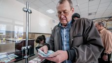 Мужчина получает пенсию в почтовом отделении. Архивное фото Мужчина получает пенсию в почтовом отделении. Архивное фото