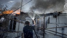 Мужчина тушит пожар в станице Луганская после авиаудара. Архивное фото Мужчина тушит пожар в станице Луганская после авиаудара. Архивное фото
