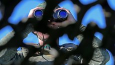 Военнослужащий смотрит в бинокль. Архивное фото Военнослужащий смотрит в бинокль. Архивное фото