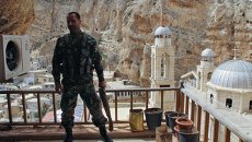 Военнослужащий сирийской армии на фоне церкви в городе Маалюля. Архивное фото Военнослужащий сирийской армии на фоне церкви в городе Маалюля. Архивное фото