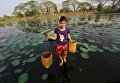 Девушка несет речную воду. Янгон, Мьянма Девушка несет речную воду. Янгон, Мьянма