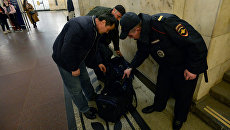 Сотрудник полиции проверяет вещи у пассажиров Московского метрополитена. Архивное фото Сотрудник полиции проверяет вещи у пассажиров Московского метрополитена. Архивное фото