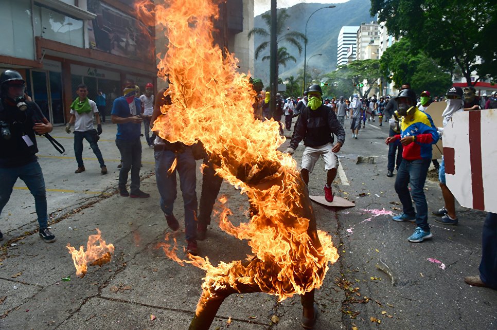 Демонстратор после взрыва бензобака полицейского мотоцикла во время столкновений в знак протеста против президента Венесуэлы Николаса Мадуро в Каракасе, 3 мая 2017