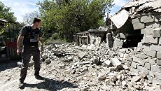 Сотрудник ОБСЕ осматривает двор жилого дома, пострадавший в результате обстрела в Донецкой области. Архивное фото Сотрудник ОБСЕ осматривает двор жилого дома, пострадавший в результате обстрела в Донецкой области. Архивное фото