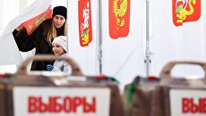 Женщина с ребенком во время голосования на выборах президента РФ на избирательном участке №13-06 в Москве. 18 марта 2018 Женщина с ребенком во время голосования на выборах президента РФ на избирательном участке №13-06 в Москве. 18 марта 2018