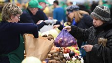 Посетители у торговых рядов на рынке. Архивное фото Посетители у торговых рядов на рынке. Архивное фото