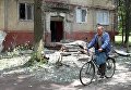 Мужчина едет на велосипеде во дворе жилого дома, пострадавшего в результате обстрела, в поселке Горловка Донецкой области Мужчина едет на велосипеде во дворе жилого дома, пострадавшего в результате обстрела, в поселке Горловка Донецкой области