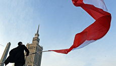 Мужчина держит польский флаг в Варшаве. Архивное фото Мужчина держит польский флаг в Варшаве. Архивное фото