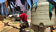 Женщина набирает воду в палаточном лагере для сирийских беженцев. Архивное фото Женщина набирает воду в палаточном лагере для сирийских беженцев. Архивное фото