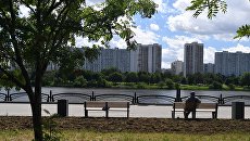 Мужчина сидит на лавочке на набережной Москвы-реки на территории парка 850-летия Москвы в районе Марьино Мужчина сидит на лавочке на набережной Москвы-реки на территории парка 850-летия Москвы в районе Марьино