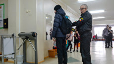 Сотрудник службы безопасности проверяет ученика в средней общеобразовательной школе Сотрудник службы безопасности проверяет ученика в средней общеобразовательной школе