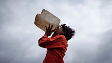 Мальчик пьет воду из канистры на фоне муссоных облаков в городе Карачи Мальчик пьет воду из канистры на фоне муссоных облаков в городе Карачи